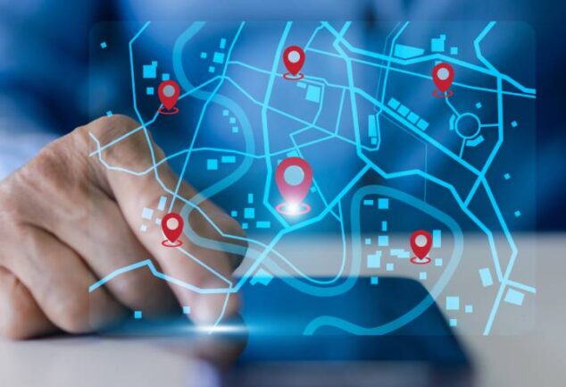 Mão de gestor interagindo com interface digital de mapa e pins de localização em tempo real, ilustrando o uso de sistemas inteligentes para o rastreamento de veículos e monitoramento de frota.