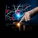 Mão de usuário operando smartphone com interface de mapa digital e pins de geolocalização flutuantes, demonstrando o uso do otimizador de rotas do Google para planejamento logístico avançado.