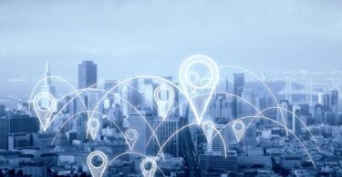 Panorama urbano de metrópole com conexões digitais e pins de localização flutuantes, ilustrando o uso estratégico da geolocalização para expansão de negócios e análise de mercado.