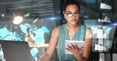 Uma mulher em traje profissional usando um tablet enquanto cercada por displays digitais futuristas e visualizações de análise.