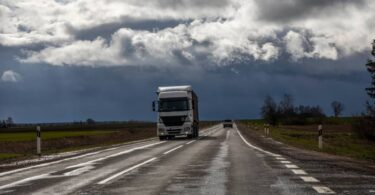Um caminhão dirigindo por uma estrada sob um céu nublado. Representa os dados de condições climáticas oferecidos pela API Weather.