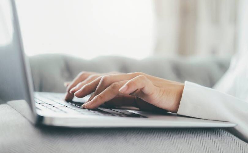 Mão em close-up utilizando um computador portátil. Uso da tecnologia de conexão online para negócios, educação e comunicação.