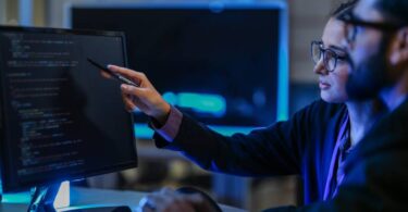 Desenvolvedores analisando linhas de código em um monitor de alta resolução, representando a infraestrutura robusta e a engenharia por trás do Google Antigravity.