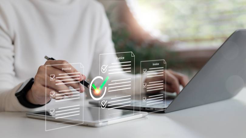Close de mãos assinando faturas digitais com selo de verificação verde, destacando a segurança e validade jurídica da assinatura eletrônica em ambiente corporativo.