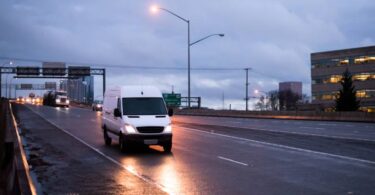 Van de carga branca trafegando em rodovia ao entardecer, ilustrando a importância da roteirização para garantir entregas pontuais e economia de combustível na logística urbana.