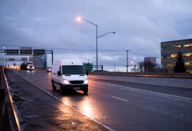 Van de carga branca trafegando em rodovia ao entardecer, ilustrando a importância da roteirização para garantir entregas pontuais e economia de combustível na logística urbana.