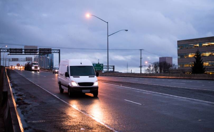 Van de carga branca trafegando em rodovia ao entardecer, ilustrando a importância da roteirização para garantir entregas pontuais e economia de combustível na logística urbana.