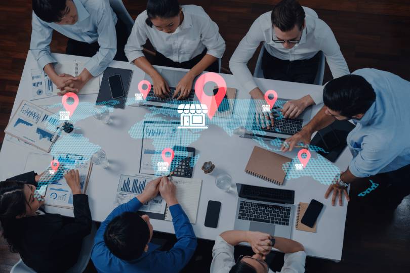 Equipe de planejamento analisando mapa digital com pins de localização para traçar a estratégia de expansão geográfica em field service, garantindo maior cobertura de mercado e eficiência operacional.