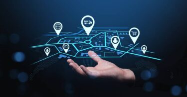 Mão segurando interface holográfica de mapa com ícones de rastreamento, representando o monitoramento em tempo real para garantir o cumprimento do OTIF na logística de transporte.