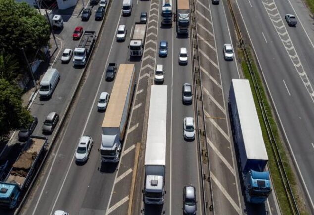 Vista aérea de rodovia com fluxo intenso de caminhões e carros, ilustrando a aplicação de tecnologias de roteirização para reduzir opex em frotas logísticas.