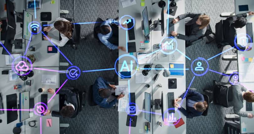 Visão aérea de escritório com rede de ícones de inteligência artificial conectando colaboradores, ilustrando o processo de grounding para garantir respostas baseadas em dados proprietários e confiáveis.