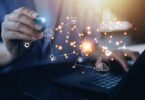 Consultor interagindo com uma rede digital holográfica de IA conectada a ícones de nuvem, segurança e engrenagens, representando a atuação de Especialistas em Agentes de IA na infraestrutura e governança do Gemini Enterprise.