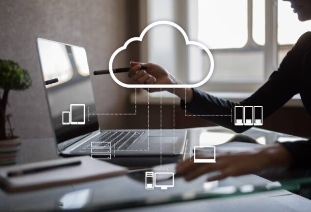 Uma mulher sentada em uma mesa com um laptop e uma nuvem acima dela. Ícones em destaque que representam tecnologia de computação em nuvem.